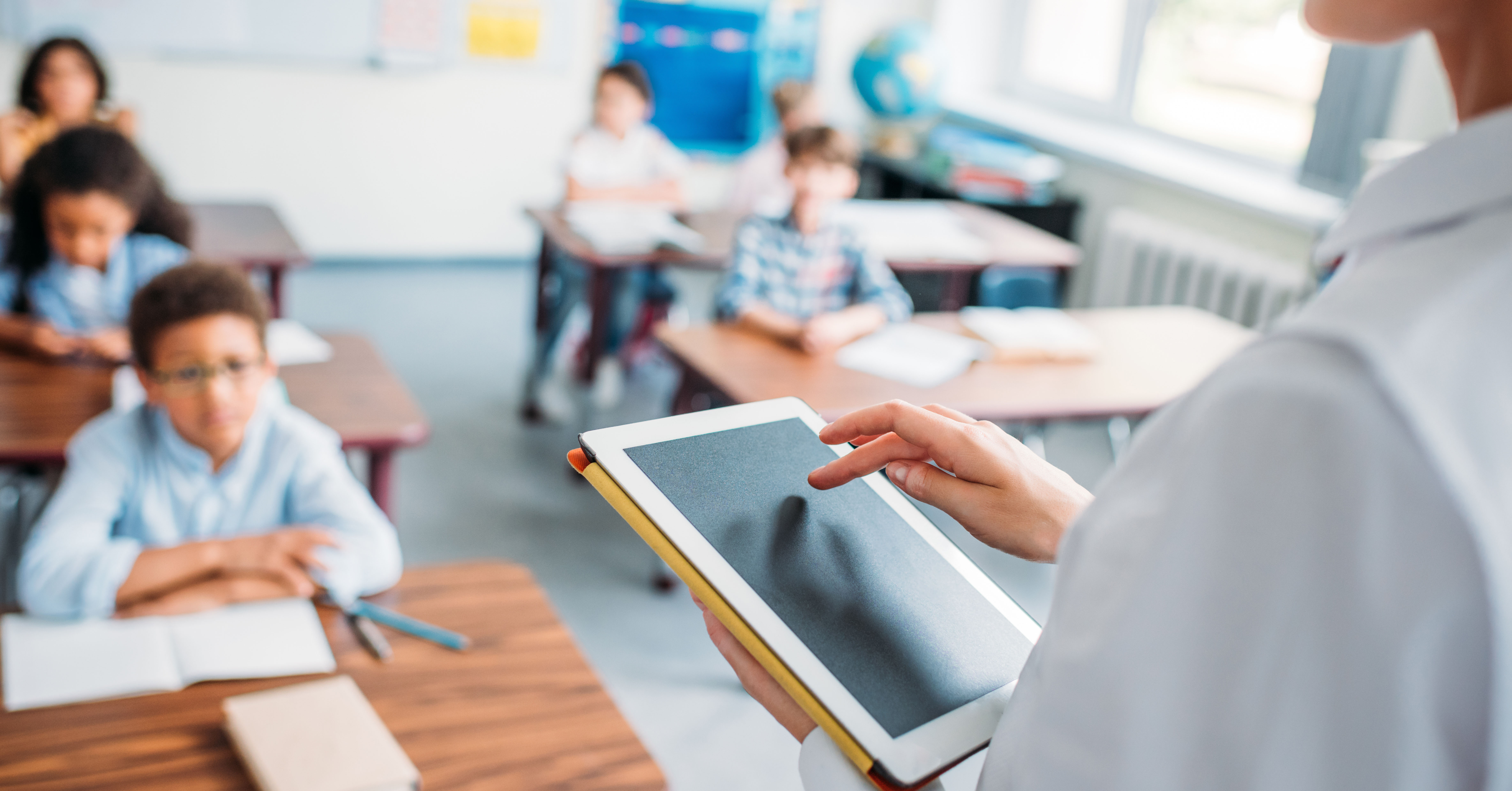 A teacher stands at the front of a classroom 